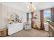 Bright bedroom featuring a white dresser, mirror, chair, crib and a modern chandelier at 146 Allenton Way, Statesville, NC 28677