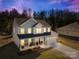 Inviting two-story home with a cozy front porch and attached two-car garage at dusk at 146 Allenton Way, Statesville, NC 28677