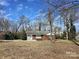 View of the exterior showcasing a brick home with a stone accent wall and a large front yard at 154 Bingham Dr, Charlotte, NC 28213