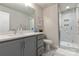 Modern bathroom featuring gray cabinetry, quartz countertops, and a glass-enclosed shower with marble tiling at 2014 Bryant Park Dr, Charlotte, NC 28208