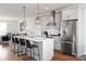 Open kitchen boasts gray cabinets, a stainless steel refrigerator, a center island with seating, and modern pendant lighting at 2014 Bryant Park Dr, Charlotte, NC 28208
