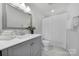 Well-lit bathroom featuring a gray vanity, decorative mirror, and shower with a white shower curtain at 261 Helton Ln, Fort Mill, SC 29708