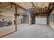 Unfinished basement featuring exposed ceiling beams, a concrete floor, and a set of white garage doors at 2845 Wood Gate Rd, Lincolnton, NC 28092