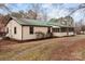 Exterior shot of house with green metal roof, shed, gravel driveway, and landscaped beds at 2845 Wood Gate Rd, Lincolnton, NC 28092