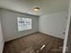 The carpeted bedroom features a light color palette and natural light from the window at 514 Meadowrock Dr, Albemarle, NC 28001