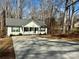 Charming single-story home with white siding, gray roof, and a concrete driveway surrounded by a wooded landscape at 514 Meadowrock Dr, Albemarle, NC 28001