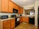 Efficient kitchen with wood cabinets, black appliances, and a pass-through to the dining area at 120 Snead Rd, Fort Mill, SC 29715