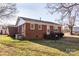 Rear exterior view of a red brick home displaying its quaint design and well-kept surrounding yard at 132 Kennedy Ave, Kannapolis, NC 28083