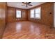Spacious living room featuring wood paneling, ceiling fan, and ample natural light from two windows at 132 Kennedy Ave, Kannapolis, NC 28083