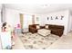 Inviting living room with comfortable sofas, plush ottoman, playroom area, and neutral leaf patterned rug at 137 Tenth Green Ct, Statesville, NC 28677