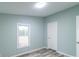 A clean bedroom featuring light walls, a window, modern wood-look flooring, and a simple door at 1912 Beach Ln, Heath Springs, SC 29058