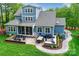 Spacious backyard with an outdoor patio, fire pit, grill, dining area, and lush landscaping at 208 Cape August Pl, Belmont, NC 28012