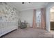 Charming Bedroom with floral wallpaper, a crib, a rocking chair, and soft pink curtains at 208 Cape August Pl, Belmont, NC 28012