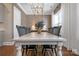 Bright dining room with hardwood floors, farmhouse table, modern chandelier, buffet, and large windows with sheer curtains at 208 Cape August Pl, Belmont, NC 28012