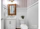 Charming powder room featuring stylish mirror, modern vanity, and unique wallpaper, complemented by neutral wainscoting at 208 Cape August Pl, Belmont, NC 28012
