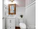 Charming powder room featuring patterned wallpaper, white wainscoting, and a framed mirror at 208 Cape August Pl, Belmont, NC 28012