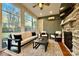 Cozy sunroom with stone fireplace, comfortable seating, ceiling fan, and lots of natural light through the large windows at 208 Cape August Pl, Belmont, NC 28012