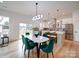 Sunlit dining area with green velvet chairs and a modern chandelier, leading into a well-equipped kitchen at 2511 Dundeen St, Charlotte, NC 28216