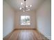 Well-lit empty room with a modern chandelier and large windows at 2511 Dundeen St, Charlotte, NC 28216