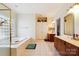 Bright bathroom featuring a tub, tile flooring, dual sinks, and wooden cabinets at 3536 Wylie Meadow Ln, Charlotte, NC 28269