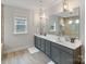Modern bathroom with double vanity, sleek gray cabinetry, large mirror and tile flooring at 4159 Millstream Rd, Denver, NC 28037