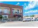 Attractive brick building with black awnings, outdoor tables, and street parking in a vibrant neighborhood setting at 5380 Village Dr # 203, Concord, NC 28027