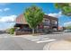 Brick restaurant building with outdoor patio seating and umbrellas, enhanced by lush tree and crosswalk views at 5380 Village Dr # 203, Concord, NC 28027