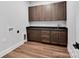 Laundry room area with dark wood cabinetry, sink, dark countertop, and wood flooring at 6055 Brush Crk, Monroe, NC 28110