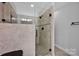 Modern glass enclosed shower features pebble floor, neutral tile, and dark fixtures at 662 Georgie St, Troutman, NC 28166