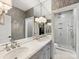 Elegant bathroom with double sinks, a large mirror, textured wallpaper, and a glass-enclosed shower at 6711 Conservatory Ln, Charlotte, NC 28210