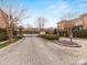 Gated community entrance with landscaped median, mature trees and attractive brick architecture at 6711 Conservatory Ln, Charlotte, NC 28210