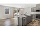 Well-lit kitchen boasts stainless appliances, gray cabinets, wood floors, and a granite island with a stainless dishwasher at 7535 Meridale Forest Dr # 107, Charlotte, NC 28269
