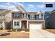 Charming two-story home with a brick and blue siding exterior, complemented by a well-manicured lawn and an attached two-car garage at 1051 Lookout Shoals Dr, Fort Mill, SC 29715