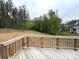 An outdoor wooden deck with railings overlooks the serene, wooded backyard with lush greenery at 157 Powder Spring Dr, Statesville, NC 28677