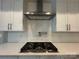 Close up of a modern gas cooktop, stainless steel range hood and subway tile backsplash at 157 Powder Spring Dr, Statesville, NC 28677