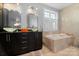 Bright bathroom features double vanity, soaking tub, natural stone tiling, and lots of natural light at 4915 Ardenwoods Dr, Charlotte, NC 28215