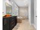 Bright bathroom featuring a double vanity, soaking tub, and walk-in shower with natural stone tiling at 4915 Ardenwoods Dr, Charlotte, NC 28215