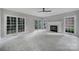 Bright, expansive living room featuring large windows, plush carpeting, a ceiling fan, and a cozy fireplace at 907 Thorn Ridge Ln, Lake Wylie, SC 29710