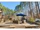 Stone patio with an outdoor fireplace and comfortable seating surrounded by tall trees at 9135 Fair Oak Dr, Sherrills Ford, NC 28673