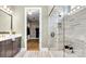 Elegant bathroom featuring a glass shower with white tile surround, a modern vanity, and a view to the walk-in closet at 1047 Rabbit Hill Ln, Monroe, NC 28110