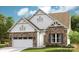 Charming two-story home featuring stone and white siding accents, a two-car garage and a well-manicured lawn at 1047 Rabbit Hill Ln, Monroe, NC 28110