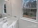 Bathroom vanity with a large mirror and a window view of the trees at 10906 Falls Branch Ln, Charlotte, NC 28214