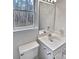 Bathroom featuring a white sink vanity, faucet, and toilet with a window and mirror at 10906 Falls Branch Ln, Charlotte, NC 28214