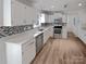 Kitchen featuring stainless appliances, white cabinets, mosaic tile backsplash, and wood floors at 10906 Falls Branch Ln, Charlotte, NC 28214