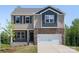 Two-story home boasts a stone facade, light brown siding, a two-car garage and manicured front lawn at 111 Rustling Waters Dr, Mooresville, NC 28117