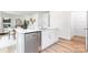 Modern kitchen island includes a stainless steel dishwasher, white cabinets, and light wood floors at 111 Rustling Waters Dr, Mooresville, NC 28117