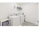 Functional laundry room featuring a washer, dryer, storage shelves and decorative floor tiles at 112 Buoy Ln, Statesville, NC 28677
