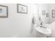 Neutral powder room featuring a pedestal sink, decorative mirror, and subtle artwork, creating a clean and elegant space at 112 Buoy Ln, Statesville, NC 28677