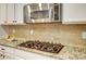 Close-up of the granite countertop, gas cooktop, and stainless steel microwave at 1126 Snowbird Ln, Waxhaw, NC 28173