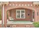 Close-up view of a brick-arched porch featuring a swing and green striped rug at 119 Hemphill Ave, Chester, SC 29706